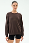 A person stands facing forward, wearing the SPLITS59 Andie Oversized Fleece Sweatshirt in Dark Chocolate and black shorts against a plain light background.