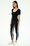 A woman stands against a white background wearing the SPLITS59 Ashby Rib Short Sleeve in black, paired with black leggings featuring white and blue side stripes and white sneakers.