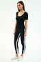 A woman stands against a white background wearing the SPLITS59 Ashby Rib Short Sleeve in black, paired with black leggings featuring white and blue side stripes and white sneakers.