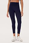 A person is shown from the shoulders down, wearing dark blue Bianca High Waist Rigor 7/8 - Indigo leggings by SPLITS59 and white sneakers against a plain background.