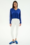 A woman faces forward, modeling the SPLITS59 Ellie Fleece V Neck Sweatshirt in cobalt/white with white sleeve stripes, paired with white leggings and blue athletic shoes, against a plain white backdrop.