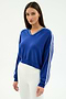 A woman wears the SPLITS59 Ellie Fleece V Neck Sweatshirt in Cobalt/White with white pants, standing against a plain light background for an effortless athletic look.
