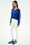 A woman wears the SPLITS59 Ellie Fleece V Neck Sweatshirt in Cobalt/White with white leggings and blue athletic shoes, creating a relaxed athletic look against a plain white background.