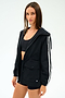 A woman wears the SPLITS59 Reggie Water Repellent Jacket in Black/White over a black sports bra and shorts, standing against a plain white background.