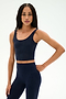 A woman stands against a plain background with one hand on her hip, wearing the SPLITS59 Sprint Rigor Bralette in Indigo and matching high-waisted leggings, highlighting multi-sport performance style and supportive sports bra design.