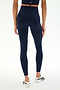 A person is shown from the back, standing on a white background, wearing SPLITS59’s Sprint High Waist Rigor 7/8 leggings in Indigo—premium workout leggings crafted from Rigor fabric—paired with a matching crop top and white ballet-style shoes.