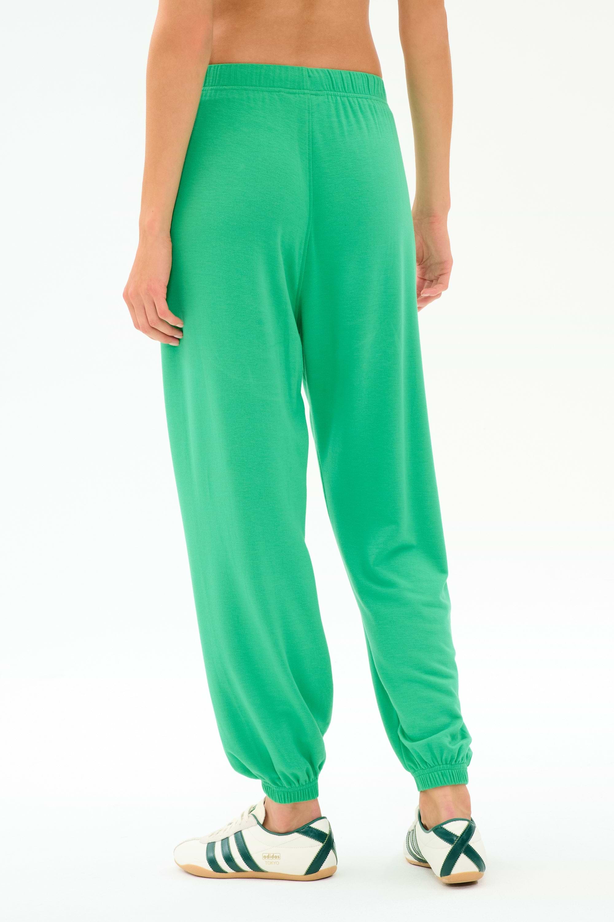 Model wears the SPLITS59 Andie Oversized Fleece Sweatpant in Spearmint, shown from the back with white sneakers accented by green stripes, against a plain white background.