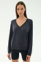 A woman stands against a light background, wearing the SPLITS59 Bennie Fleece V Neck Sweatshirt in Graphite and black shorts. This chic pullover is crafted in Los Angeles.