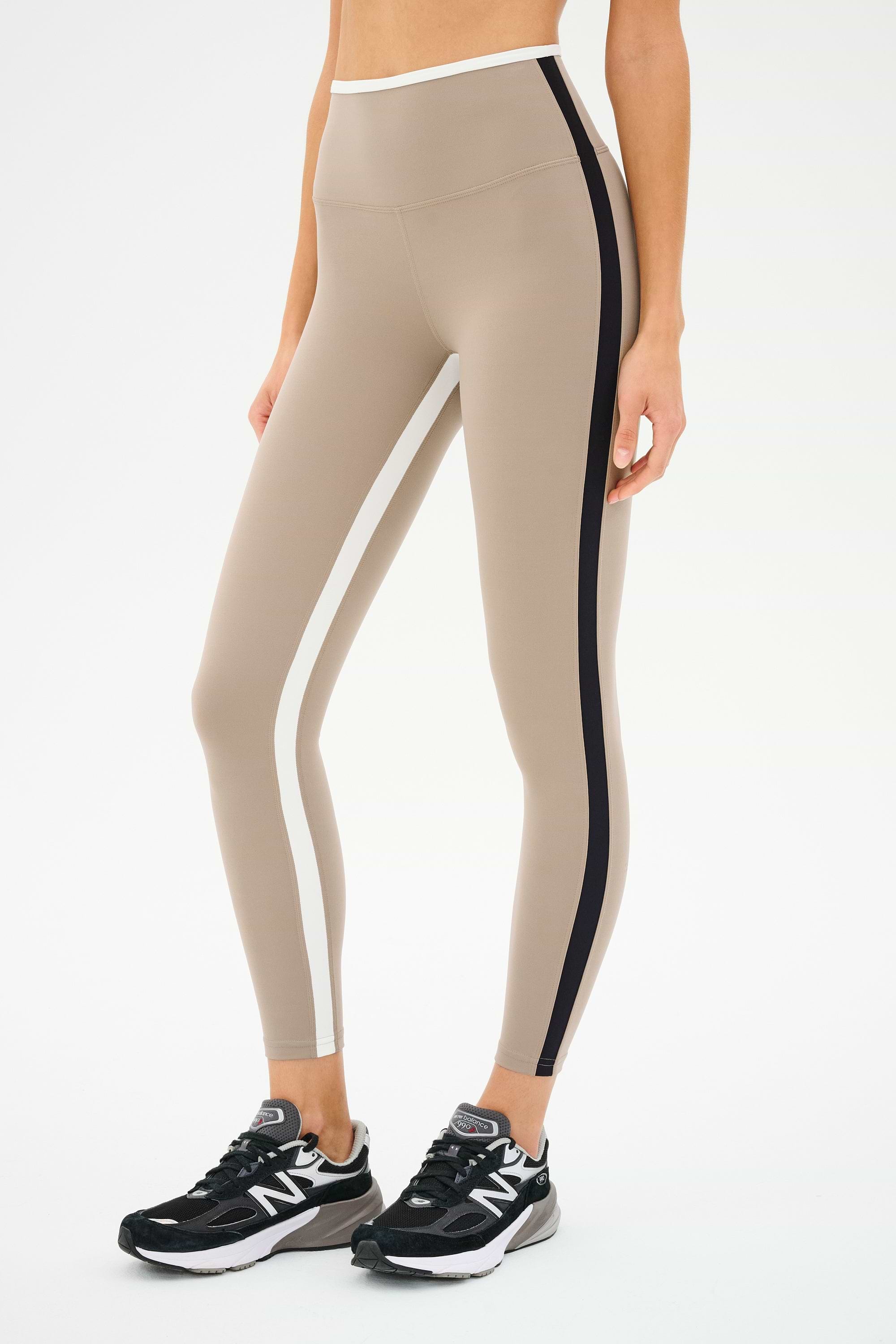Someone is sporting the SPLITS59 Sam High Waist Rigor 7/8 leggings in Latte/Black, along with black New Balance sneakers.