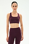 A woman stands against a plain light background wearing the SPLITS59 Lexi Rigor Bra in Dark Cherry/Black, paired with matching high-waisted leggings.