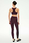 A person stands facing away, wearing the SPLITS59 Margot Rigor Legging in Dark Cherry/Black paired with a matching sports bra and black athletic shoes, perfect for gym workouts, against a plain white background.