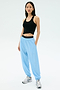 A woman stands against a plain background wearing the Splits59 Ashby Rib Tank in black, paired with light blue jogger pants and white sneakers.