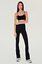 Full front view of woman with dark straight hair wearing black high waist below ankle length legging with wide flared bottoms and black racerback bra with spaghetti straps. Paired with white and gray shoes.