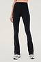 Front view of woman wearing black high waist below ankle length legging with wide flared bottoms. Paired with white and gray shoes.
