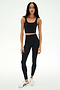 A woman stands against a white background, wearing a black crop top, white sneakers, and the SPLITS59 Sprint High Waist Rigor 7/8 leggings in black—crafted from durable Rigor fabric.