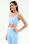 A woman poses confidently in the SPLITS59 Sprint Rigor Bra - Skylight, ready for multi-sport performance against a plain white background.