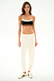 Woman in a black sports bra, SPLITS59 Andie Oversized Fleece Sweatpant - Creme made in Los Angeles, and white sneakers—ideal for cool weather workouts.