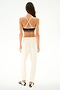 Woman facing away in SPLITS59 Andie Oversized Fleece Sweatpant - Creme and a black sports bra—ideal for cool weather workouts—against a white background.