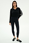 A woman wears the SPLITS59 Ellie Fleece V Neck Sweatshirt in Black/White, featuring white stripes, paired with black leggings and black sneakers with white accents, standing against a plain background.