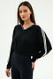 A woman stands against a plain background, wearing the SPLITS59 Ellie Fleece V Neck Sweatshirt in Black/White and black leggings designed for comfort and flexibility.