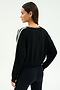 A woman stands with one hand on her hip, modeling the SPLITS59 Ellie Fleece V Neck Sweatshirt in Black/White and black spandex blend leggings, facing away from the camera against a plain background.