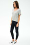 A woman stands against a plain background, wearing the SPLITS59 Georgia Jersey V-Neck in Heather Grey, paired with black leggings and white sneakers featuring black stripes.