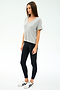 A woman stands against a plain background, wearing the SPLITS59 Georgia Jersey V-Neck in Heather Grey, paired with black leggings and white sneakers featuring black stripes.