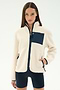 A woman models the SPLITS59 Harris Sherpa Jacket in Creme/Indigo, featuring navy zippers and front pockets, paired with black shorts against a plain white background.