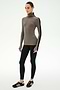 A woman stands against a white background wearing the SPLITS59 Jackson Rib Full Length Turtleneck in Lentil/Black—a soft modal spandex blend top with black striped sleeves—paired with black leggings and black sneakers.