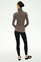 A person stands with their back to the camera against a plain white background, wearing the SPLITS59 Jackson Rib Full Length Turtleneck in Lentil/Black.