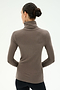 A person with dark hair in a bun wears the SPLITS59 Jackson Rib Full Length Turtleneck in Lentil, paired with black pants, standing with their back to the camera against a light background.