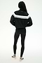 A person stands with their back to the camera against a plain white background, wearing the SPLITS59 Morrison Nylon Twill Track Jacket in Black/Creme, paired with black spandex leggings and white sneakers.