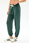 Wearing the SPLITS59 Andie Oversized Fleece Sweatpant in Military, styled with white sneakers featuring green stripes—perfect for cool weather workouts—standing against a plain white background.