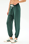 Wearing the SPLITS59 Andie Oversized Fleece Sweatpant in Military, styled with white sneakers featuring green stripes—perfect for cool weather workouts—standing against a plain white background.
