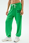A person wears the SPLITS59 Andie Oversized Fleece Varsity 59 Sweatpant in Grass/59, featuring a bright green color, white drawstring, and number 59 on the left thigh with white athletic shoes against a plain background.