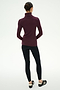 A person stands with their back to the camera, wearing the SPLITS59 Jackson Rib Full Length Turtleneck in Dark Cherry/Creme, paired with black leggings and black sneakers against a plain white background.