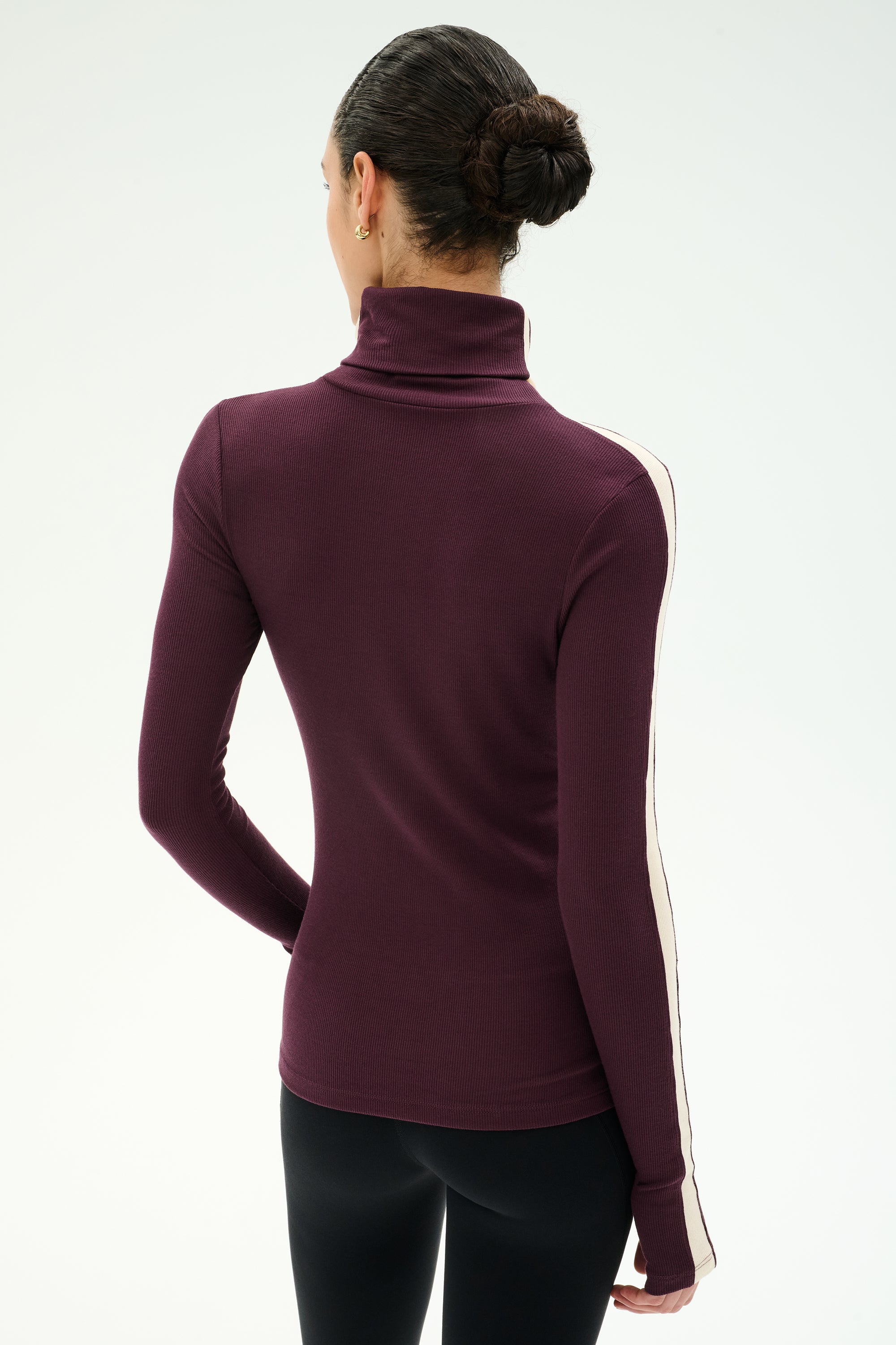 A person with their hair in a bun is shown from the back, wearing the SPLITS59 Jackson Rib Full Length Turtleneck in Dark Cherry/Creme—a comfortable modal blend top with spandex for added stretch, featuring a white stripe along the sleeve—against a plain background.