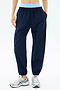 Model wearing SPLITS59 Megan Woven Nylon Jogger in Indigo, featuring elastic cuffs and a light blue waistband, paired with white sneakers and hands in pockets, standing against a plain background.