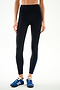 Wearing SPLITS59 Clare High Waist Rigor 7/8 - Black/Cobalt leggings with a blue side stripe and blue sneakers, standing against a light background.