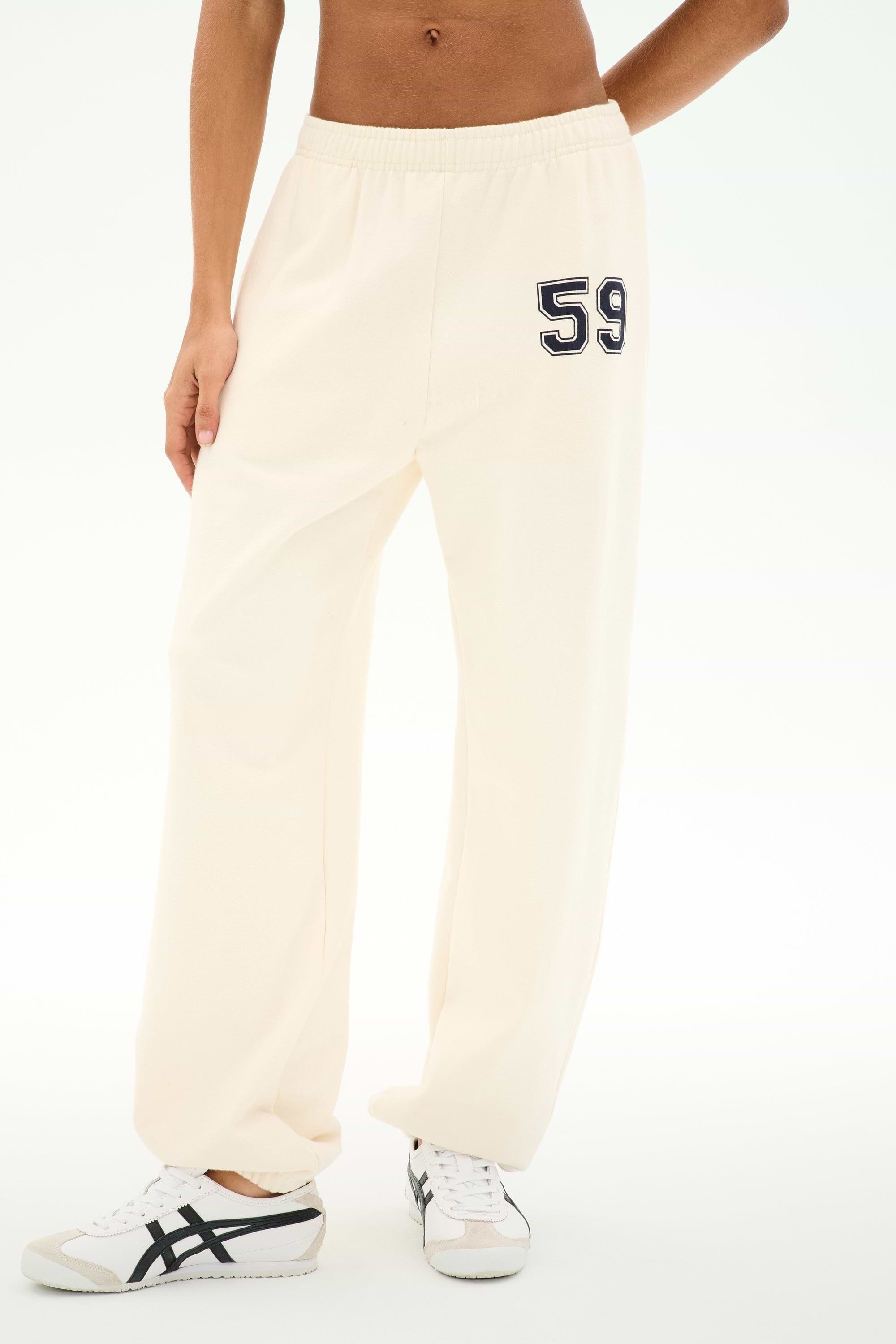 Dressed in the SPLITS59 Serena French Terry Oversized Sweatpant in creme, featuring soft cotton fabric and the number 59 printed on the left hip, paired with white sneakers.