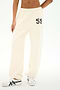Dressed in the SPLITS59 Serena French Terry Oversized Sweatpant in creme, featuring soft cotton fabric and the number 59 printed on the left hip, paired with white sneakers.