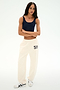 A person stands against a white background wearing a navy tank top, SPLITS59 Serena French Terry Oversized Sweatpant in Creme/59 made from soft cotton fabric, and white sneakers with a black design.