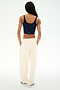 A person stands with their back to the camera against a plain white background, wearing a navy cotton tank top, white sneakers, and the SPLITS59 Serena French Terry Oversized Sweatpant in Creme/59.