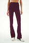 A person wears the SPLITS59 Raquel High Waist Supplex Flare leggings in Dark Cherry/Creme, featuring a high-waisted fit, soft spandex fabric, and white stripe detailing, paired with white sneakers and standing against a plain background.