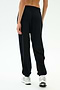 A person wears SPLITS59’s Andie Oversized Fleece Varsity 59 Sweatpant in Black/59 with white sneakers, standing on a white background and facing away from the camera—perfect for cool weather workouts.