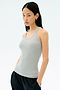 A woman with long dark hair wears the Splits59 Ashby Rib Tank in Lt. Heather Grey and black pants, standing with her hands in her pockets against a plain light background.