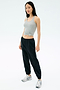 A woman faces forward, wearing the Splits59 Ashby Rib Tank in Lt. Heather Grey, paired with black jogger pants and white athletic sneakers, set against a plain white background.