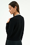 A woman with long brown hair faces away, looking down against a plain background, wearing the SPLITS59 Bekah Knit Cardigan in black and white.