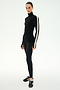 A person wearing the SPLITS59 Jackson Rib Full Length Turtleneck in Black/Creme, which features a white stripe on the sleeve, paired with black leggings and black athletic shoes, standing against a white background.
