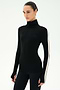 A woman wears the SPLITS59 Jackson Rib Full Length Turtleneck in Black/Creme, featuring a white stripe down the sleeve, as she stands against a plain light background.
